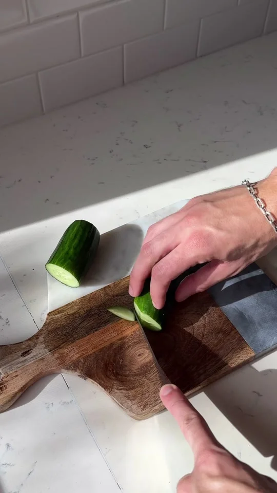 Mãos do Chef cortando pepino para a salada.